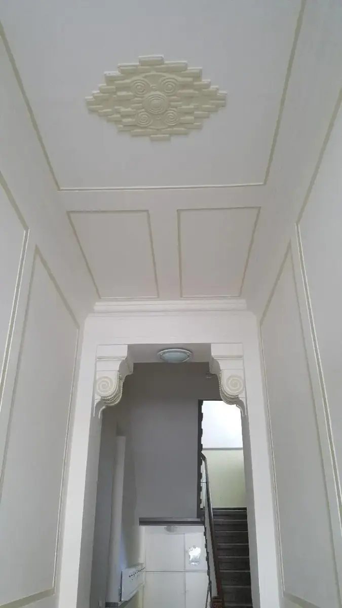 Ein Flur mit Decke und Treppe in einem Haus.