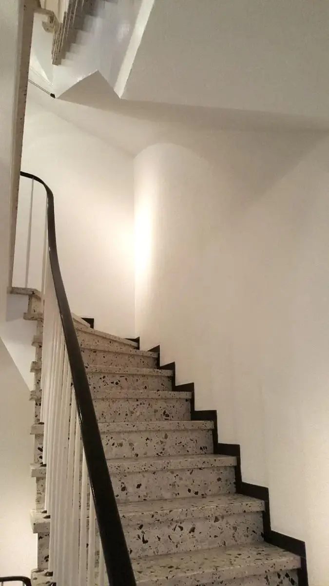 Eine Treppe mit schwarzem Geländer und weißer Wand
